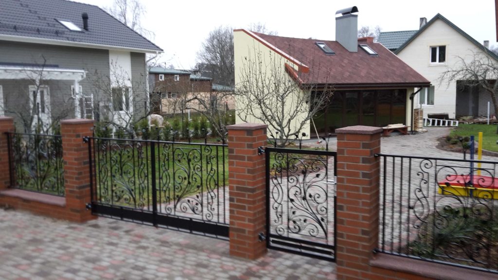 a gate and brick fence with a house in the background